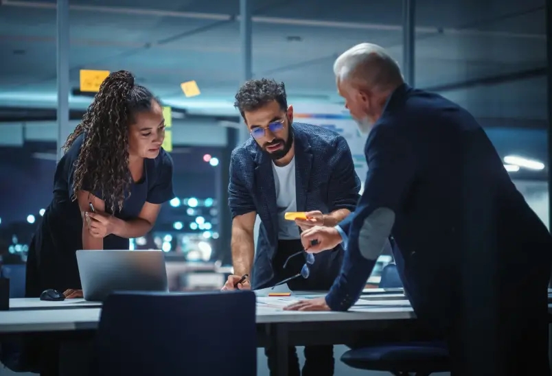 Group of three individuals huddled around a smart device, captivated by what they see on the screen