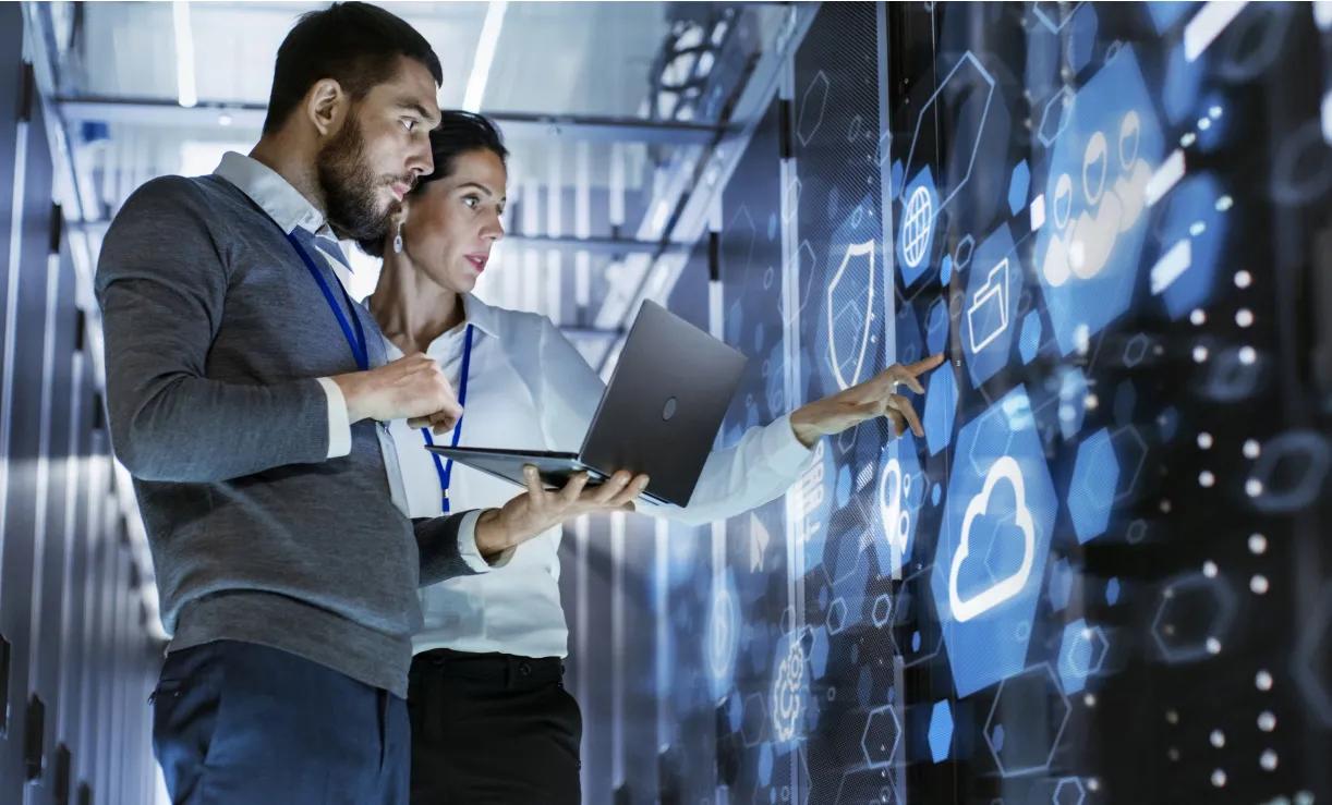 Two individuals viewing a computer screen displaying cloud icons for telecom cloud services.