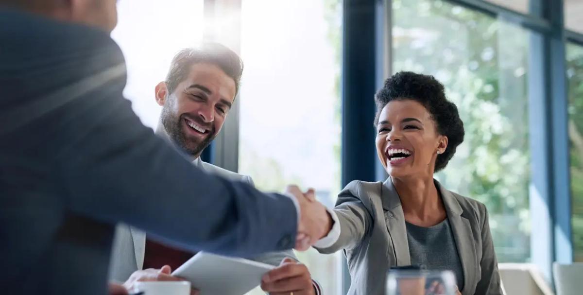 Business professionals sealing a deal with a handshake in an office, signifying collaboration.