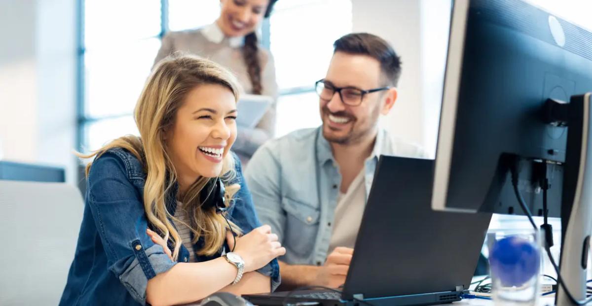 A man and woman smiling at a desk, the ideal partners for software development solutions.